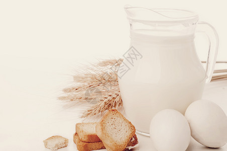 白色背景上装有牛奶小麦种子和两个的玻璃壶色调照片图片