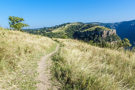 南非自然保护区中带有岩石悬崖和蓝天空背景的登山足迹路径风图片