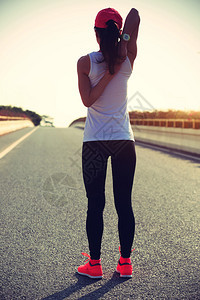 年轻健身女子赛跑者在路上热身图片