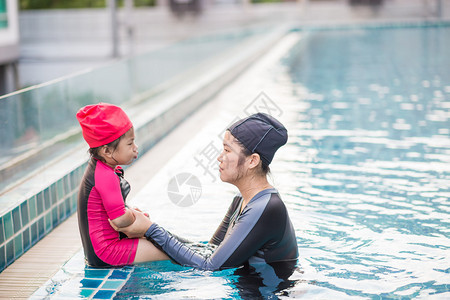 年轻活跃的母亲在游泳池玩得开心和亚洲孩子图片