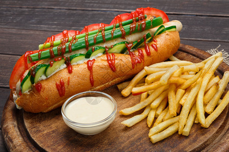 热狗和炸薯条美国快餐厅美食热狗与芹菜黄瓜蛋黄酱和番茄酱和一堆薯片在桌背景图片