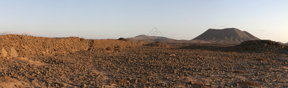 从Majanicho小渔村到主要城镇Corralejo的土路上的石墙和山背景图片