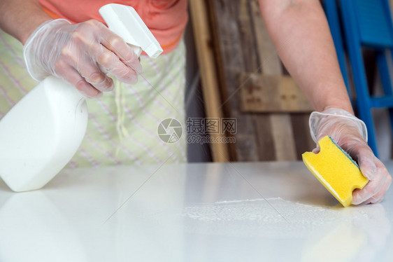 使用液体喷雾和黄线清洗白桌的人用图片