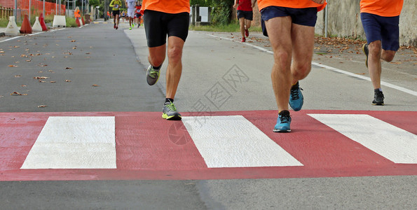 在城市马拉松赛跑中快速跑步者在一个带红色和白条纹的图片