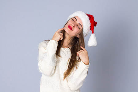 穿着白毛衣的漂亮年轻美女长发和红圣诞帽在工图片