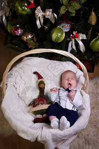 小男孩打扮成绅士睡在圣诞树下面的草棍背景图片