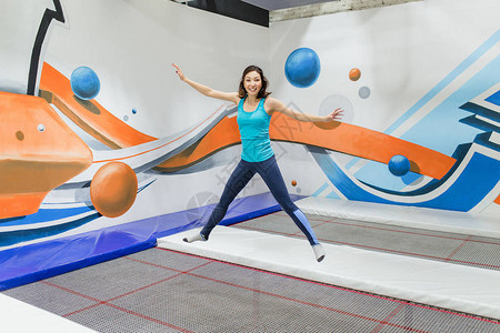 年轻女运动员在健身公园的蹦床上跳跃在室图片