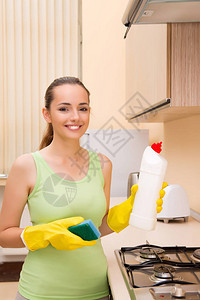 拿着瓶子打扫厨房的年轻妻子图片