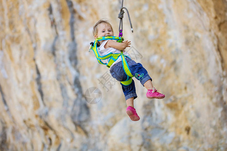穿着登山装备的小女孩挂在安全带上的绳子上图片