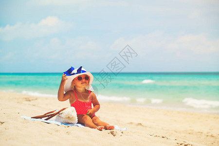 穿着大帽子的可爱小女孩在热带海滩上图片