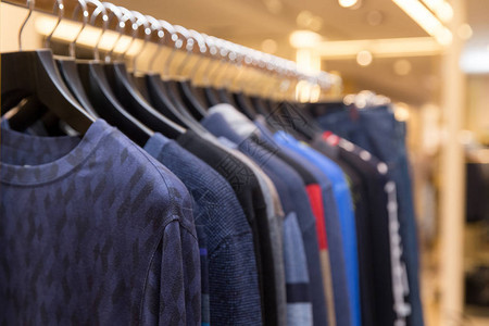 零售服装店的衣架上挂着不同颜色的男士毛衣和衬衫冬天秋季节的漂亮衣服图片