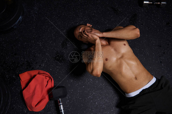 男精疲力竭的运动员躺在健身房地板图片