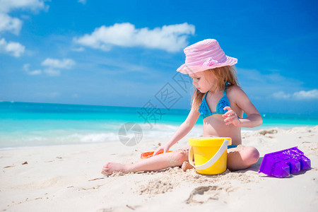 可爱的小女孩在白色的沙滩上玩沙滩玩具图片