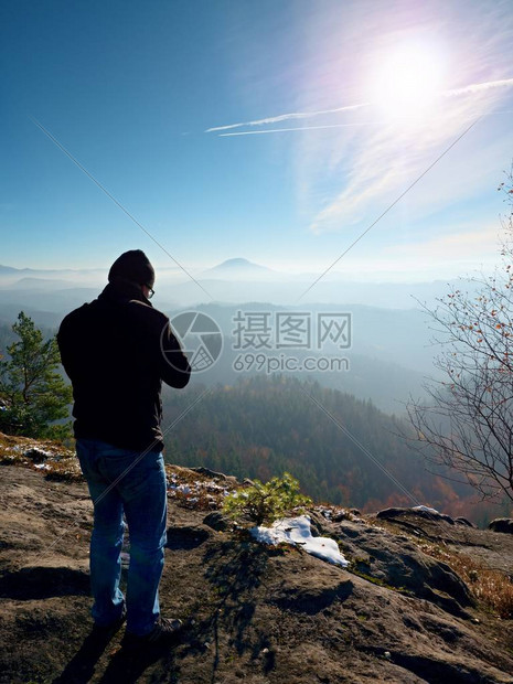高个子男人正在用脖子上的相机拍照白雪皑的岩石山峰专业摄影师在白雪皑的岩石峰顶用图片