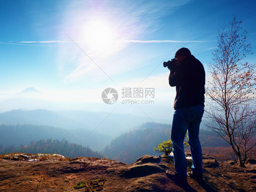 高个子男人正在用脖子上的相机拍照白雪皑的岩石山峰专业摄影师在白雪皑的岩石峰顶用图片