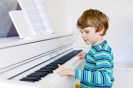 漂亮的小男孩在客厅或音乐学校弹钢琴学龄前儿童演奏乐器很开心教图片