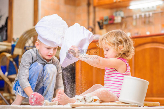 两个兄弟姐妹男孩和女孩在壁炉旁戴着厨师帽图片