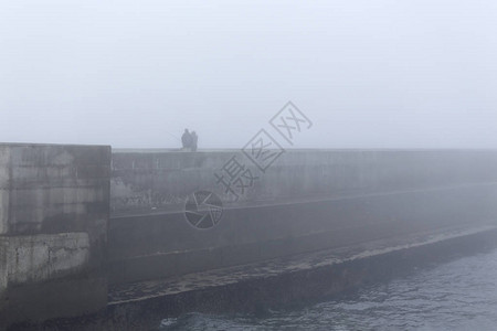 雾天在码头钓鱼的渔民图片