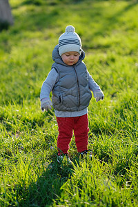 一岁大的男孩在公园草地上穿着背心夹克穿着防弹衣图片