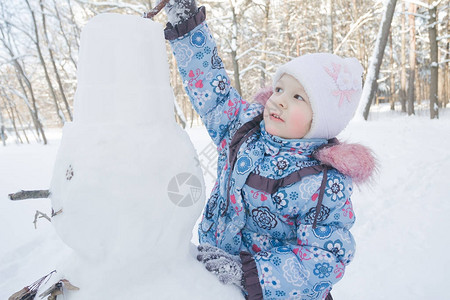 小女孩正在户外装饰冬天的雪人图片