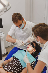 男牙医和女助理帮助在办公室的诊所治疗图片