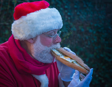 圣诞老人一大早在花园里吃大三明治吃着美味的三明治图片