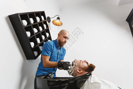 洗脸泡沫男专业美发师在黑色时尚的洗脸盆中为客户洗头背景