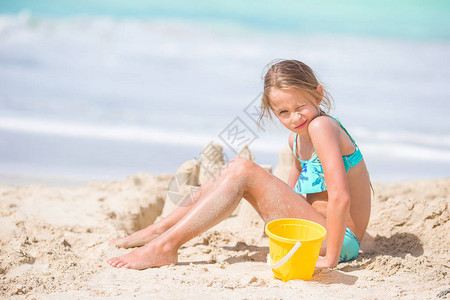 海景海报可爱的小女孩在tropial的白色沙滩上玩沙滩玩具背景