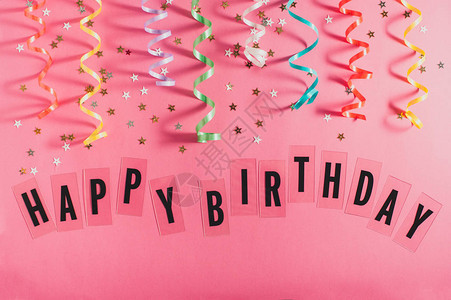 五颜六色的派对彩带的小星和粉红色背景上的文字生日快乐少女生背景图片