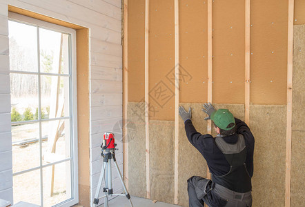 工人用一层木板完成墙面的抛光工作使用激光线水平用木纤维板材建筑隔热生态木框架房屋图片