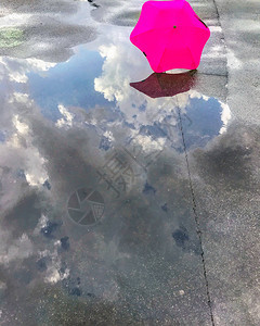 雨后水坑中的雨伞和天空的倒影图片