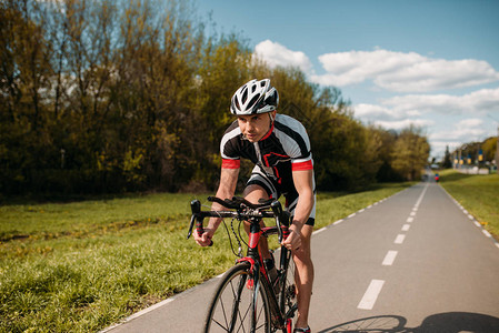 男骑自行车在头盔和运动服骑脚踏车图片