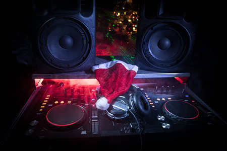 Dj混音器与耳机在黑暗的夜总会与圣诞树前夜关闭表上元素的视图节日派对的概图片