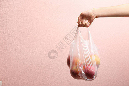 女人拿着塑料袋在彩色背景特写上放着苹果文本空间高清图片