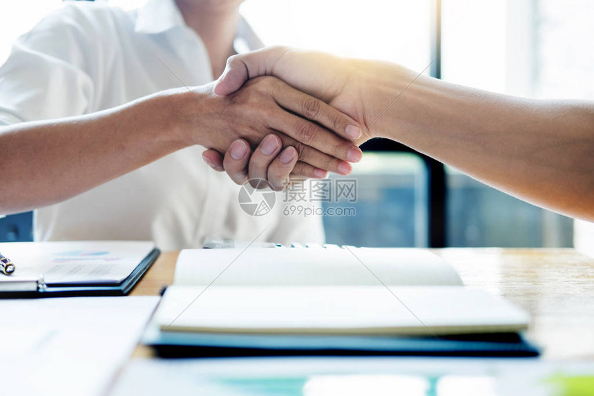 谈生意两个自信的生意人在会议结束后一起与伙伴握手成功的接洽交易理念