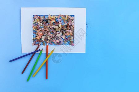 白框蓝色背景上的磨刀和彩色铅笔的木制铅笔剃图片