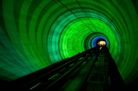 抽象发光的绿色和蓝色灯光隧道在黑暗中通过五颜六图片