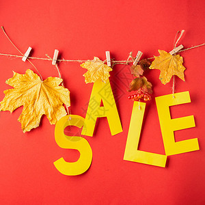 黄纸和干叶的秋季折扣信挂在红色背景的衣夹上秋季销售理念季节优惠礼图片