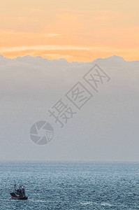 日落与美丽的橙色天空和一艘渔船在拉斯美洲海滩上的照片中相撞2019年4月11日圣克鲁斯德特内里费西班牙非洲图片