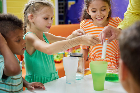 孩子们在娱乐中心做化学实验餐桌上有丰富多彩的液体的瓶子儿童派对娱图片