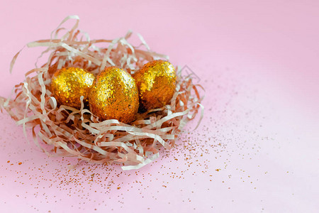 以粉红色背景为巢状的复活节金色装饰鸡蛋最小的复活节概念图片