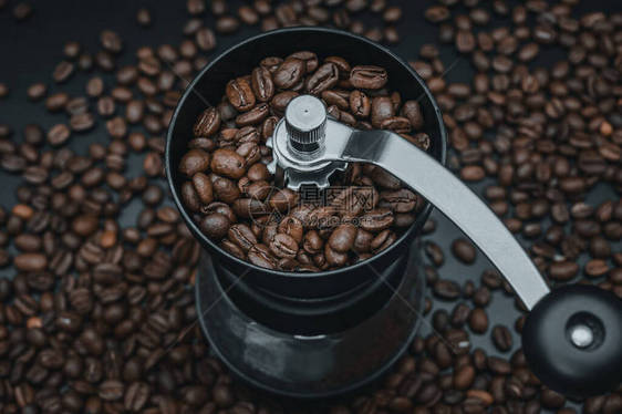 油炸咖啡豆落入手动研磨机电影般的深色为早餐准备新鲜饮料早晨咖啡磨机进行研磨在黑图片