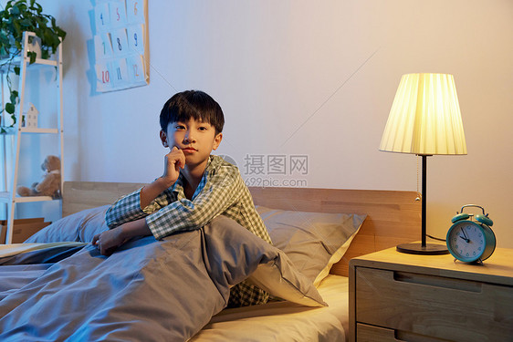 坐在床上孤单的男孩图片