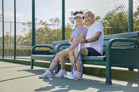 坐在网球场上休息的中老年夫妇图片