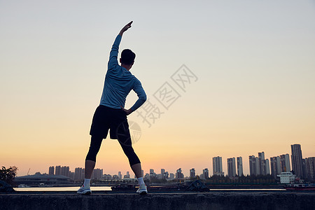 夜晚运动拉伸的男青年背影图片