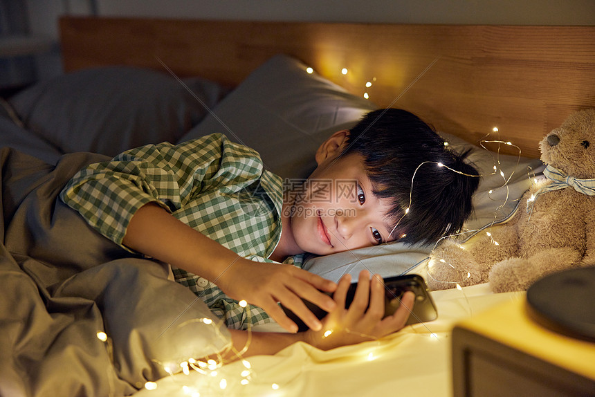 躺在床上看手机的男孩图片