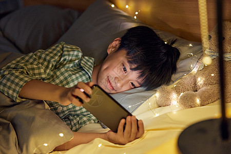 躺在床上玩手机的男孩小孩高清图片素材