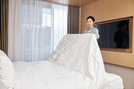 整理客房床铺的酒店女服务员图片