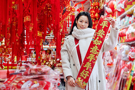 采购新年配饰的女子展示春联高清图片