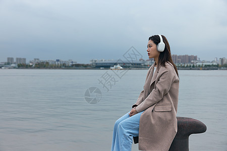 青年女性在江边带着耳机伤感情绪图片